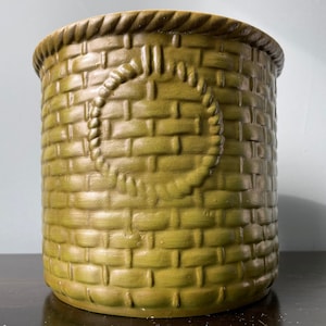 May include: A green ceramic planter with a woven basket design. The planter has a rope design around the center.