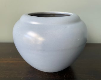 May include: A light blue ceramic planter with a rounded shape and a smooth, glossy finish.