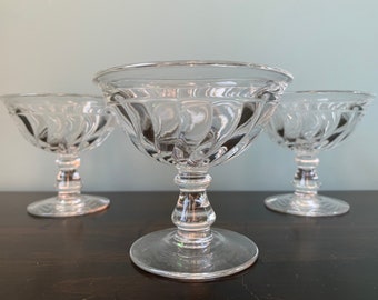 May include: Three clear glass dessert cups with a fluted design and a pedestal base.