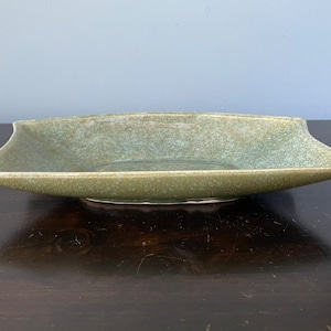 May include: A large, rectangular ceramic serving dish with a light green glaze. The dish has a slightly wavy edge and a speckled finish.