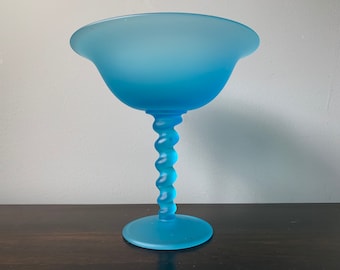 May include: A frosted blue glass bowl with a twisted stem and a wide, round base.