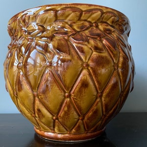 May include: A brown and gold ceramic planter with a quilted design and floral accents.