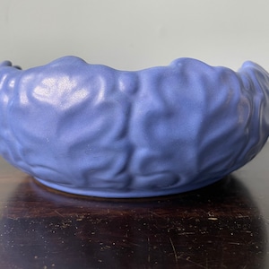 May include: A blue ceramic bowl with a textured, leaf-like design. The bowl is round and has a slightly scalloped edge.