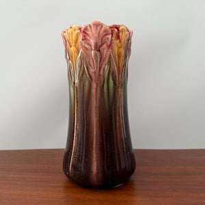 May include: A ceramic vase with a flared base and a textured, fluted body. The top edge has a scalloped design with shades of pink, yellow, and green. The vase is approximately 9 inches tall and has a glossy finish.