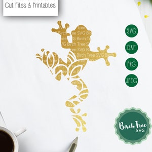 May include: A gold silhouette of a frog with intricate details, set against a white background. The image includes the text "Hand Drawn & Hand Lettered Cut Files & Printables" at the top and "Commercial & Personal Use Designs" at the bottom. The image also includes a green circle with the text "Birch Tree SVG" in white.