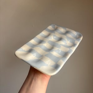 Może przedstawiać: Biały ceramiczny kubek z czarnym uchwytem i napisem "But First, Coffee" czarną, pogrubioną czcionką. Kubek stoi na białej powierzchni.