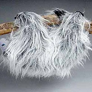 May include: A plush gray and white sloth hanging from a branch. The sloth has a long, furry body and a small, round head with black eyes.