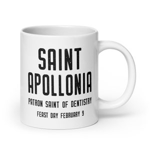 May include: White ceramic mug with black text that reads "Saint Apollonia Patron Saint of Dentistry Feast Day February 9".