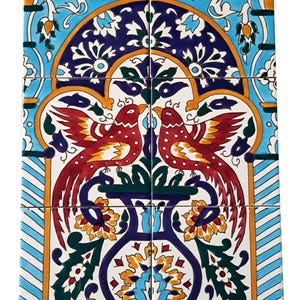 Könnte beinhalten: Ein Satz von sechs Keramikfliesen mit einem lebendigen, symmetrischen Design. Das Kunstwerk zeigt zwei rote Vögel mit langen Schwanzfedern, vor einem Hintergrund aus blauen, weißen und orangefarbenen Blumenmustern. Die Fliesen sind zu einem größeren Bild angeordnet.