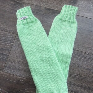 May include: A pair of light green knitted leg warmers with a silver tag that says "Boules de laine".