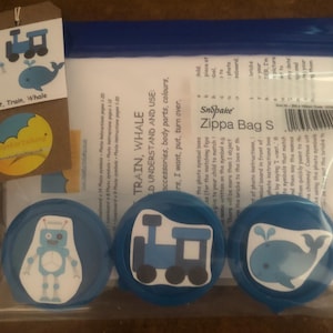 Puede incluir: Tres contenedores de plástico azul con tapas, cada uno con una imagen diferente: un robot, un tren y una ballena. Los contenedores están etiquetados como "Robot, Tren, Ballena" y forman parte de un conjunto de aprendizaje para niños. Los contenedores están en una bolsa de plástico transparente con una etiqueta que dice "Snopake Zippa Bag S".