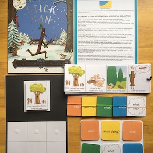 May include: A set of colorful educational cards for children featuring the story of Stick Man. The cards include images of Stick Man and his family, a dog, and a park. The cards also include question words like "who", "what", "where", and "what like?"