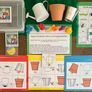 May include: A children's educational game set with a clear plastic container, flashcards, and various garden-themed toys. Includes a watering can, flower pots, and a sign that says "Bugs in the Garden".