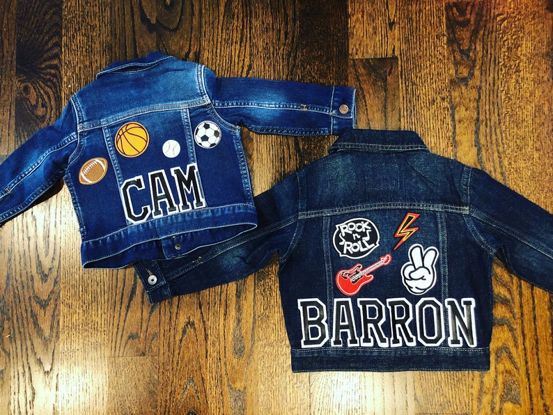 May include: Two denim jackets with personalised patches. One jacket has a basketball, baseball, football, soccer ball, and the name "CAM". The other jacket has a "Rock 'n' Roll" patch, a lightning bolt, a peace sign, a red electric guitar, and the name "BARRON".