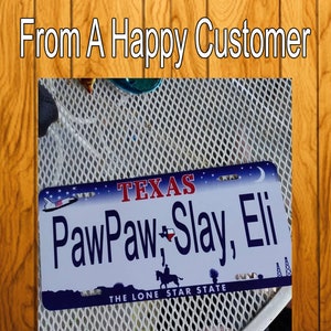 Puede incluir: Una placa de matr&iacute;cula de Texas azul y blanca con el texto "PawPaw, Slay, Eli" y "The Lone Star State".