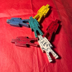 Puede incluir: Cinco piezas de rompecabezas de madera con forma de personas. Cada pieza está pintada de un color diferente: azul, verde, amarillo, rojo y blanco. La pieza blanca tiene el texto "Bill Ding Jr.".