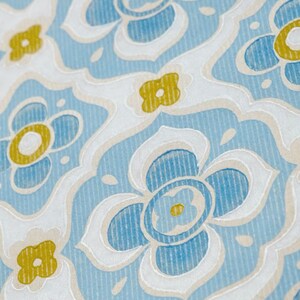 May include: A repeating pattern of blue and yellow flowers on a white background. The flowers are stylised and have a slightly raised texture.