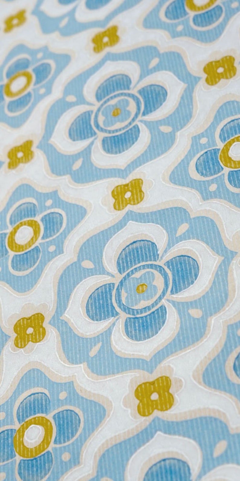 May include: A repeating pattern of blue and yellow flowers on a white background. The flowers are stylised and have a slightly raised texture.