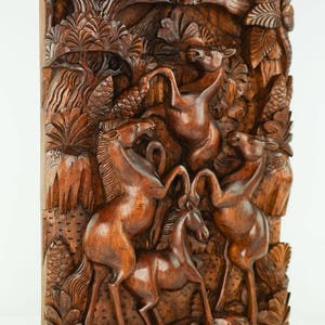 May include: A hand-carved wooden wall art piece depicting a scene of four horses in a forest. The horses are carved in a realistic style, with detailed features and flowing manes. The forest is carved with intricate details, including trees, leaves, and vines.