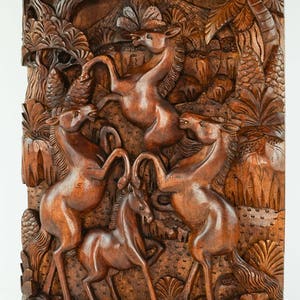 May include: A wooden wall sculpture depicting a scene of four horses in a jungle setting. The horses are carved in a realistic style and are shown in a variety of poses. The background is carved with trees, leaves, and other jungle foliage.