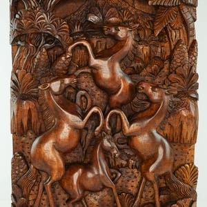 May include: A wooden wall sculpture depicting four horses in a jungle setting. The horses are carved in a realistic style and are shown in a dynamic pose. The sculpture is made of dark brown wood and has a rich, natural finish.