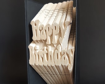 Può includere: Un libro con le parole "Happy Birthday" piegate nelle pagine. Il libro è rilegato in tessuto nero.