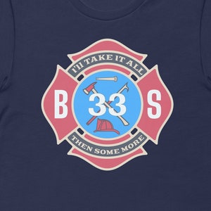 May include: Navy blue t-shirt with a red and white firefighter badge design. The badge features a crossed axe and a fire hose nozzle, with the number 33 in the center. The text around the badge reads "I'll take it all then some more" and "BOSS".