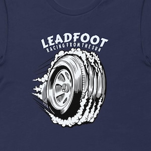 May include: Navy blue t-shirt with a white graphic of a tire with smoke coming off of it. The text "LEADFOOT RACING FROM THE SUN" is above the tire.