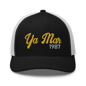 May include: Black and white trucker hat with a yellow embroidered logo that says "Ya Mar 1987".