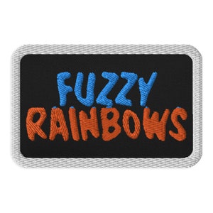 May include: A black embroidered patch with white stitching around the edges. The patch says "Fuzzy Rainbows" in blue and orange lettering.