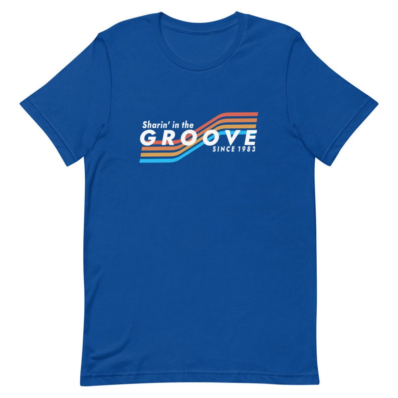 May include: A royal blue t-shirt with a retro-style graphic that says "Sharin' in the GROOVE since 1983" in white text with colorful stripes.