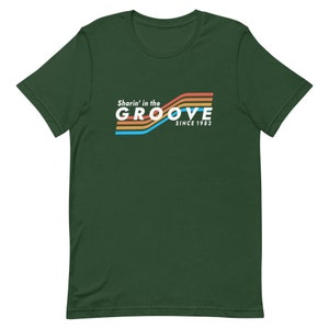 May include: A dark green t-shirt with a retro-style graphic that says "Sharin' in the GROOVE since 1983". The graphic features colorful stripes in orange, yellow, blue, and white.