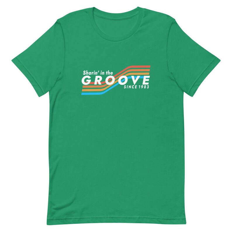 May include: Green short-sleeved t-shirt with a retro-style graphic that says "Sharin' in the GROOVE since 1983" in white text with colorful stripes.