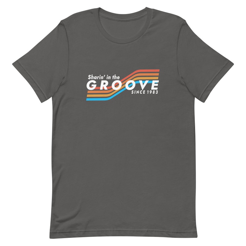 May include: A dark gray t-shirt with a retro-style graphic that says "Sharin' in the GROOVE since 1983" in white text with colorful stripes.