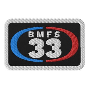 May include: A black embroidered patch with a white circle containing the text "BMFS 33". The circle is surrounded by a blue and red arc.