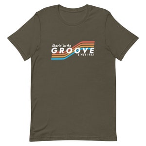 May include: A dark green t-shirt with a retro-style graphic that says "Sharin' in the GROOVE since 1983". The graphic features colorful stripes in orange, yellow, blue, and red.