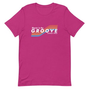 May include: Pink short-sleeved t-shirt with a retro-style graphic that says "Sharin' in the GROOVE since 1983".