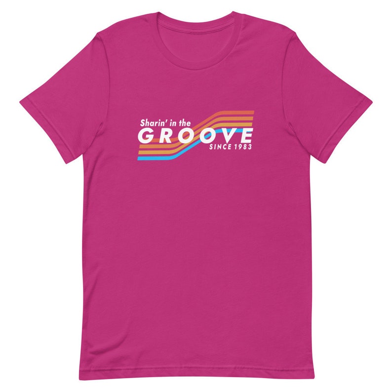 May include: Pink short-sleeved t-shirt with a retro-style graphic that says "Sharin' in the GROOVE since 1983".