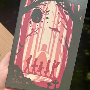 Puede incluir: Una portada de libro con una escena de bosque en tonos rosa y blanco. Se ven siluetas de personas caminando por el bosque. El texto "of a feather" está en la parte inferior izquierda.