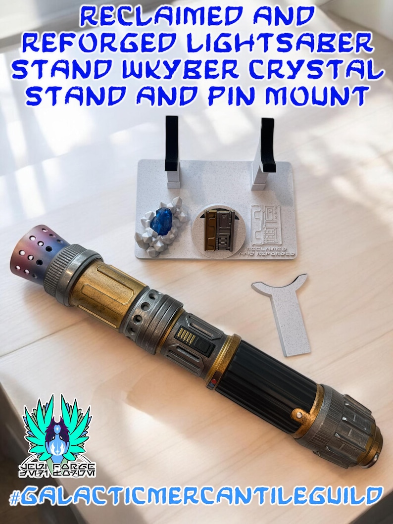 以下が含まれることがあります： 黒、金、銀色の柄のライトセーバーが、2つの黒いサポートが付いた白いスタンドに置かれています。スタンドには青いクリスタルと小さなドアのデザインもあります。テキストには「RECLAIMED AND REFORGED LIGHTSABER STAND WKYBER CRYSTAL STAND AND PIN MOUNT」と書かれています。