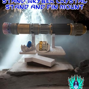 以下が含まれることがあります： Wkyberクリスタルとピンマウント付きのライトセーバーのスタンド。スタンドは、黒、金、銀のデザインのライトセーバーを保持しています。画像には「RECLAIMED AND REFORGED LIGHTSABER STAND WKYBER CRYSTAL STAND AND PIN MOUNT」と書かれています。