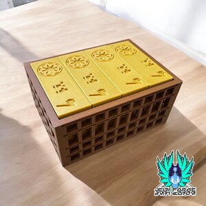 May include: A set of five gold-colored dice with different symbols on each side, stored in a brown wooden box with a grid pattern.