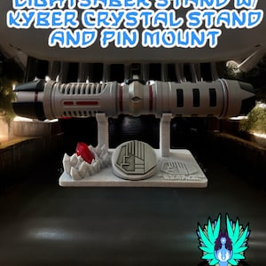 May include: A lightsaber stand with a silver lightsaber, a red kyber crystal, and a gray base with the text "Power and Control". The stand is on a black surface with a logo for the "Jedi Farce with EasyDM" and the hashtag "#GalacticMercantileGuild".