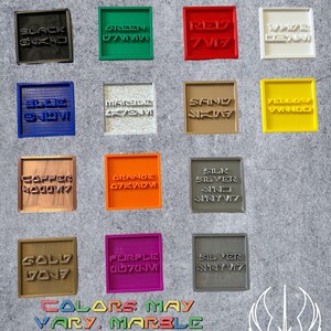 以下が含まれることがあります： 黒、緑、赤、白、青、大理石、砂、黄色など、さまざまな色の正方形のカラーサンプルコレクション。各サンプルには、様式化されたフォントのテキストがあります。画像には「Colors may vary」というテキストも含まれています。