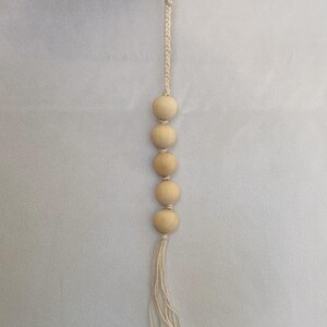 Może przedstawiać: Biały brelok z makramą z srebrnym kółkiem na klucze i pięcioma drewnianymi koralikami.