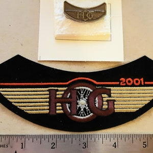 May include: A black motorcycle patch with a red and orange stripe, a brown and white wheel, and the text "H.O.G. 2001".