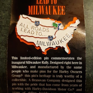 May include: A black and orange card with the text "All Roads Lead to Milwaukee" and a white outline of the United States with the text "All Roads Lead to... Milwaukee" and highway signs for US 90 and US 66. The card commemorates the inaugural Milwaukee Rally.