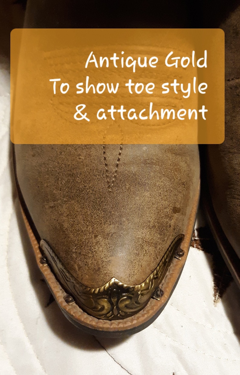 Op de afbeelding: Close-up van een bruine leren cowboylaars met een antieke gouden neus. De neus heeft een decoratief ontwerp en is bevestigd met kleine metalen klinknagels. De tekst "Antique Gold To show toe style & attachment" staat op een gele rechthoek.