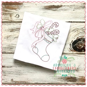 May include: A white stocking with a red bow and candy canes, surrounded by green holly leaves. The stocking is filled with candy canes and holly berries. The design is embroidered on a white fabric.
