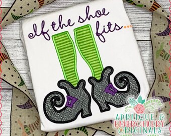 May include: A white t-shirt with the text "If the shoe fits..." embroidered in purple and green. The design includes a pair of black witch shoes with green striped stockings.